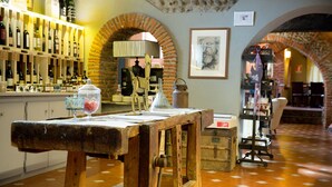 Un interior rústico con una mesa de madera, estantes llenos de botellas y arcos de ladrillo.