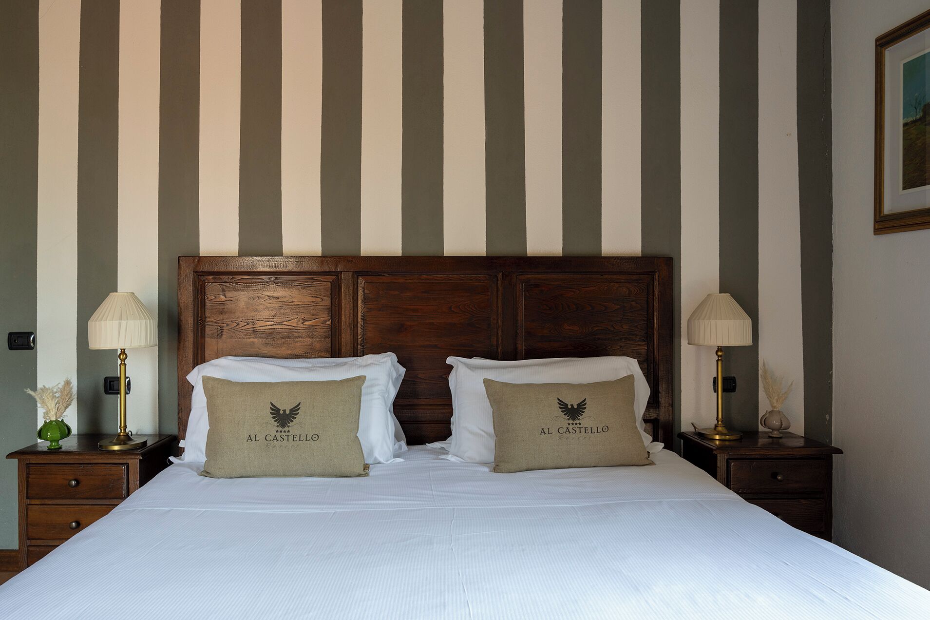 A hotel room with a large bed, two nightstands, and a wooden headboard.