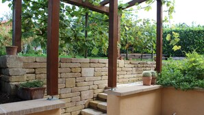 A stone bench with a metal frame, a potted cactus, and a small trash bin. - Pension Vanii (Rust)