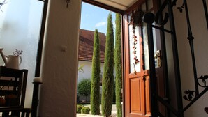 A doorway leading to a courtyard with a wooden door, a potted plant, and a wall-mounted light fixture. - Pension Vanii (Rust)
