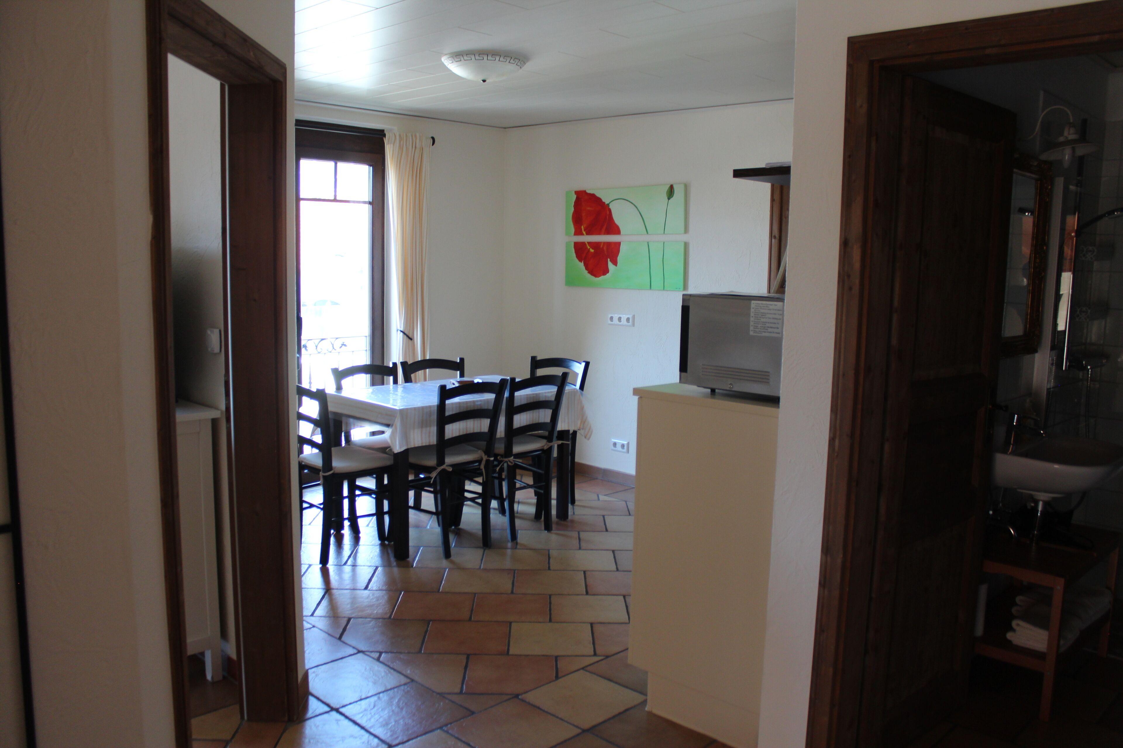 A dining area with a table and chairs, a television, and a bathroom visible through an open door.