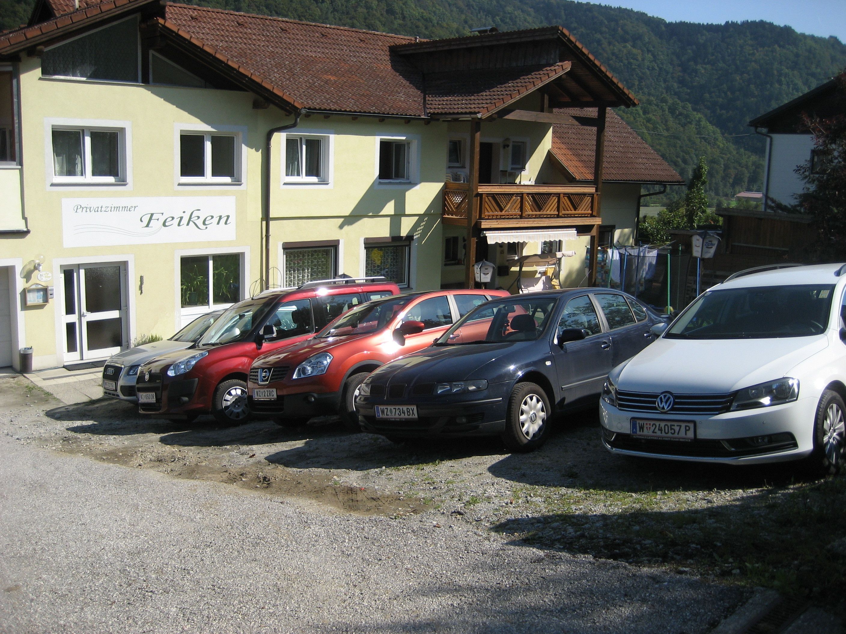 A row of parked cars in front of a building with a sign reading "Privatzimmer Feiken".