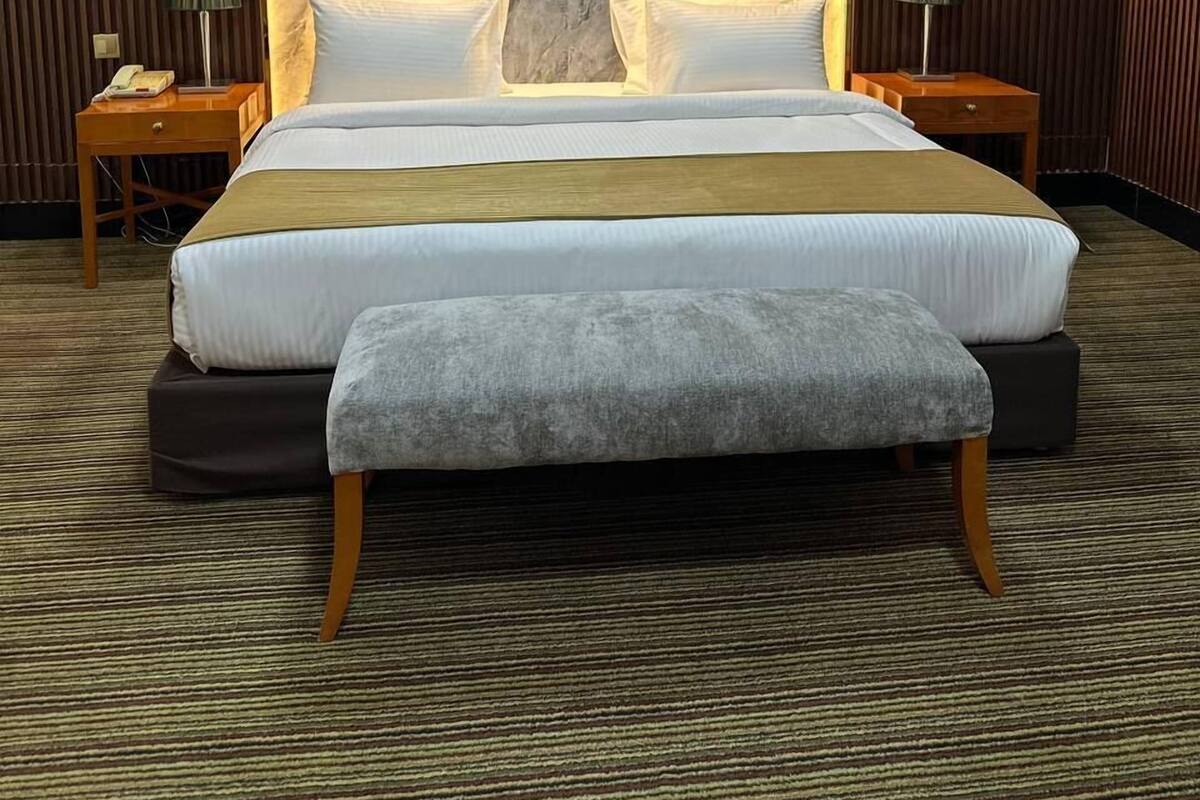 A large bed with a marble headboard, two bedside tables, and a bench.