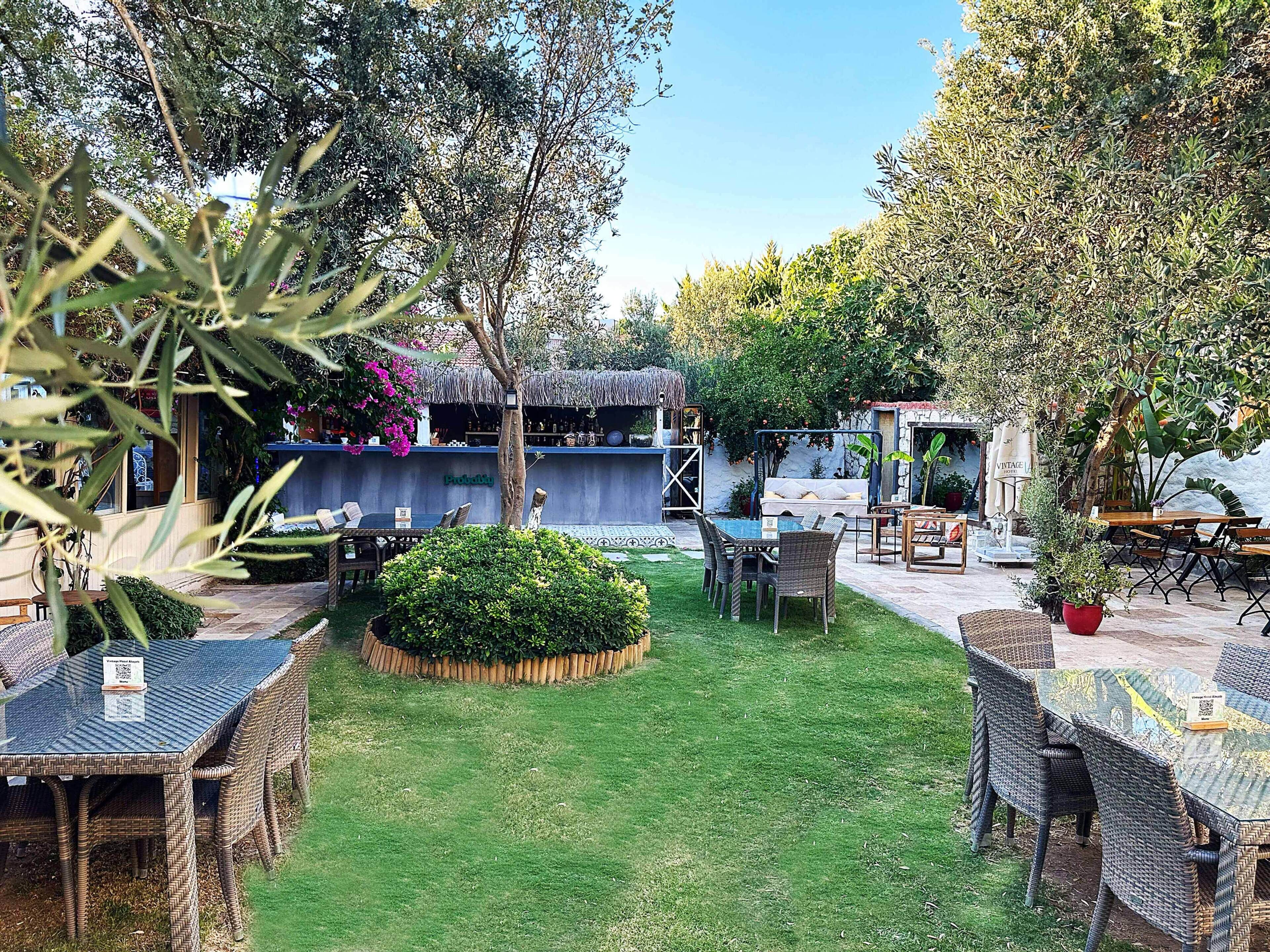 An outdoor seating area with wicker furniture, a thatched-roof bar, and a well-maintained lawn.