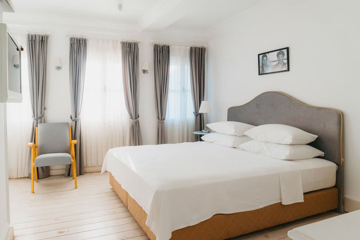 Une chambre d’hôtel avec un grand lit, une chaise, une table de chevet avec une lampe et un tableau encadré au mur.