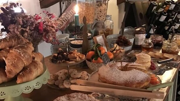 A bakery display with various baked goods, including pastries and cakes, under a wooden ceiling. - Locanda San Tomaso (Treviso)