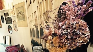 A vintage suitcase with a vase of dried flowers and books on a wooden table. - Locanda San Tomaso (Treviso)