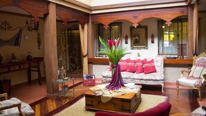 A spacious living room with a vintage suitcase as a coffee table, a sofa with red cushions, and a decorative plant. - Morenica del Rosario (Cuenca)