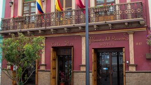 A historic hotel with a balcony, multiple flags, and a classic facade. - Morenica del Rosario (Cuenca)
