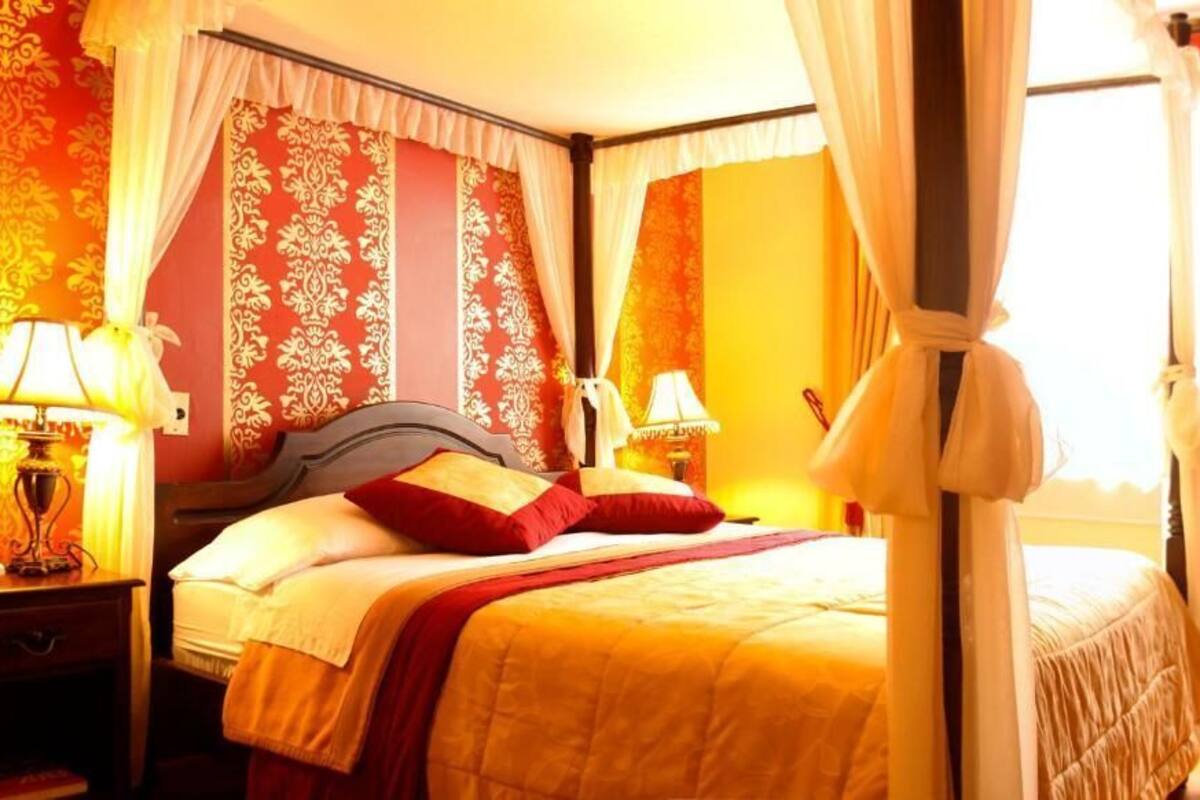 A hotel room with a bed, nightstands, lamps, and curtains.