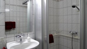 A bathroom with a white sink, a mirror, and a shower area.