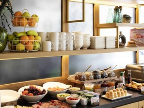 Een buffet met diverse gerechten, zoals fruit, kazen en gebak.