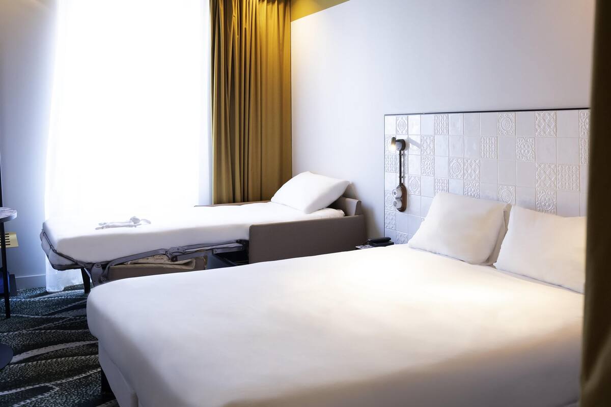 Une chambre d’hôtel avec deux lits, un bureau, un téléphone et un mur décoré d’un motif.