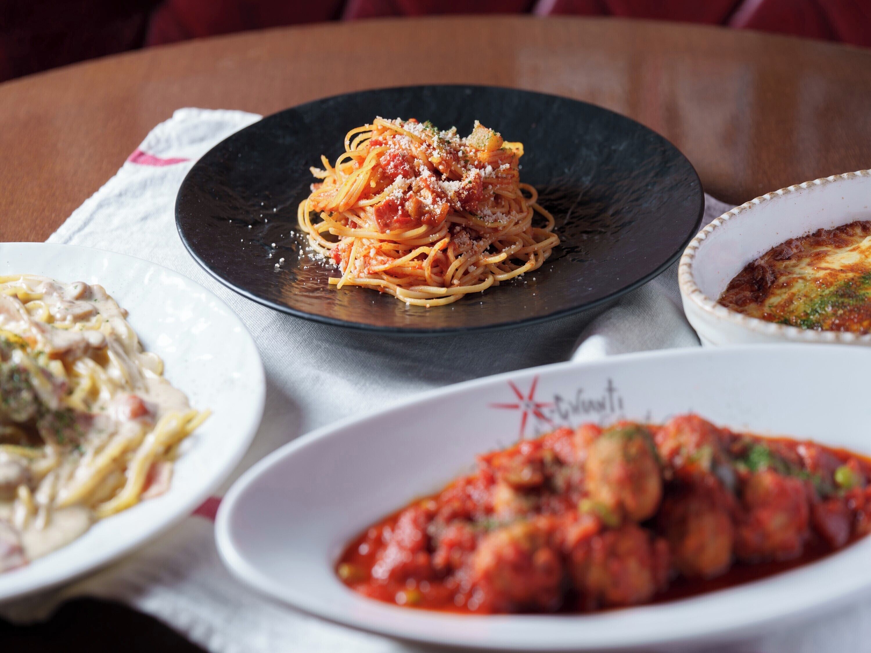 A table with three plates of pasta dishes.