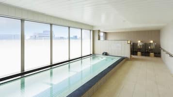 A swimming pool with a city view, a sauna area, and a tiled floor.