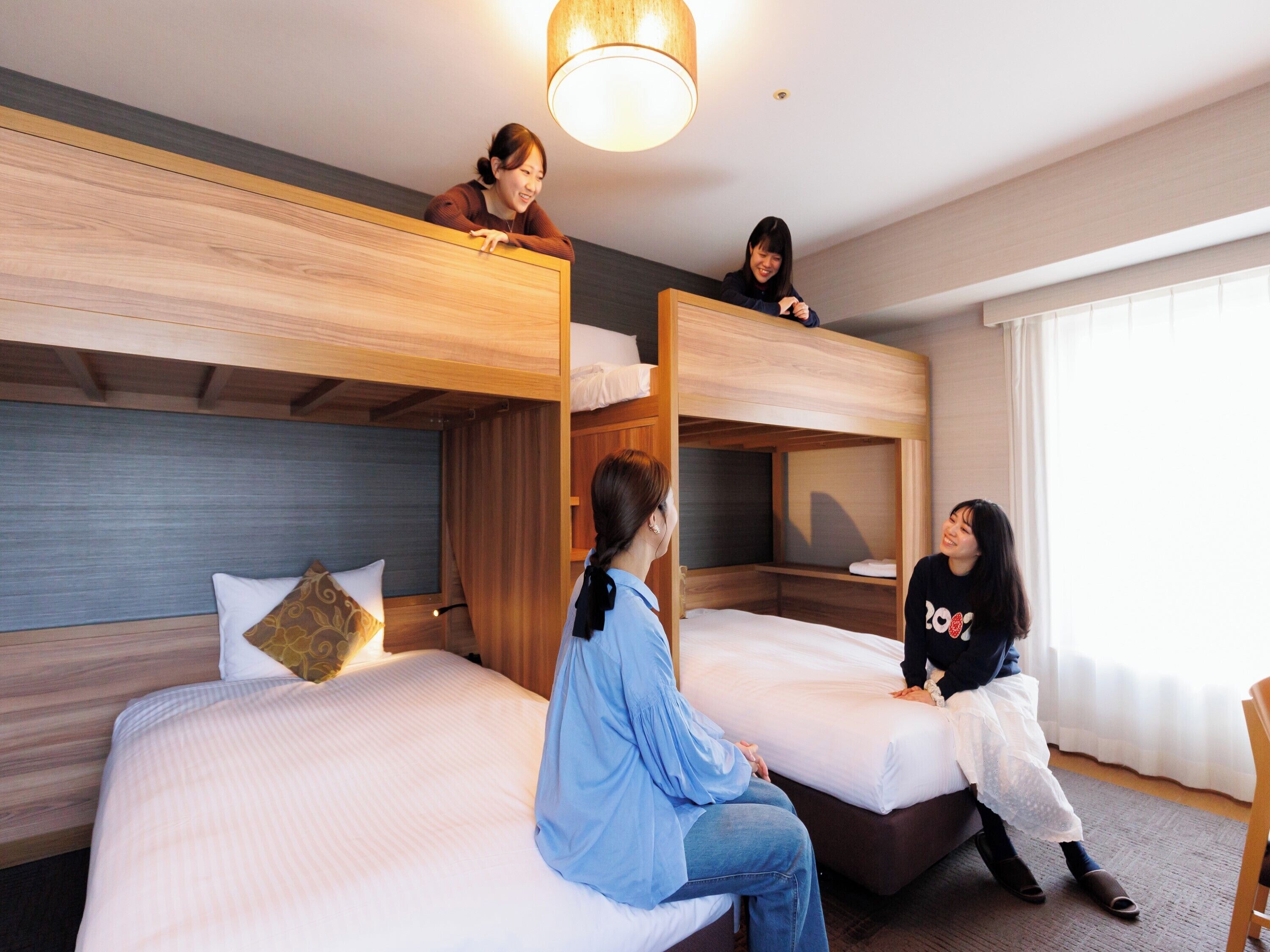 A hotel room with bunk beds, a bed with a pillow, and a wooden headboard.