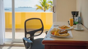 Une table à manger avec des aliments pour le petit-déjeuner, une chaise, une machine à café et une vue sur la mer.