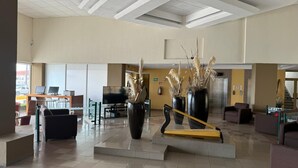 Un hall d’entrée spacieux comprenant un comptoir d’accueil, un espace détente et des plantes décoratives.