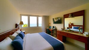 Une chambre d’hôtel avec un lit, un bureau et une grande fenêtre donnant sur la mer.