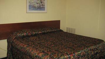 A hotel room with a bed, a framed painting on the wall, and a window with blinds.