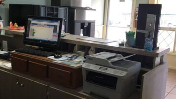 A reception desk with a computer, printer, and a small plant.
