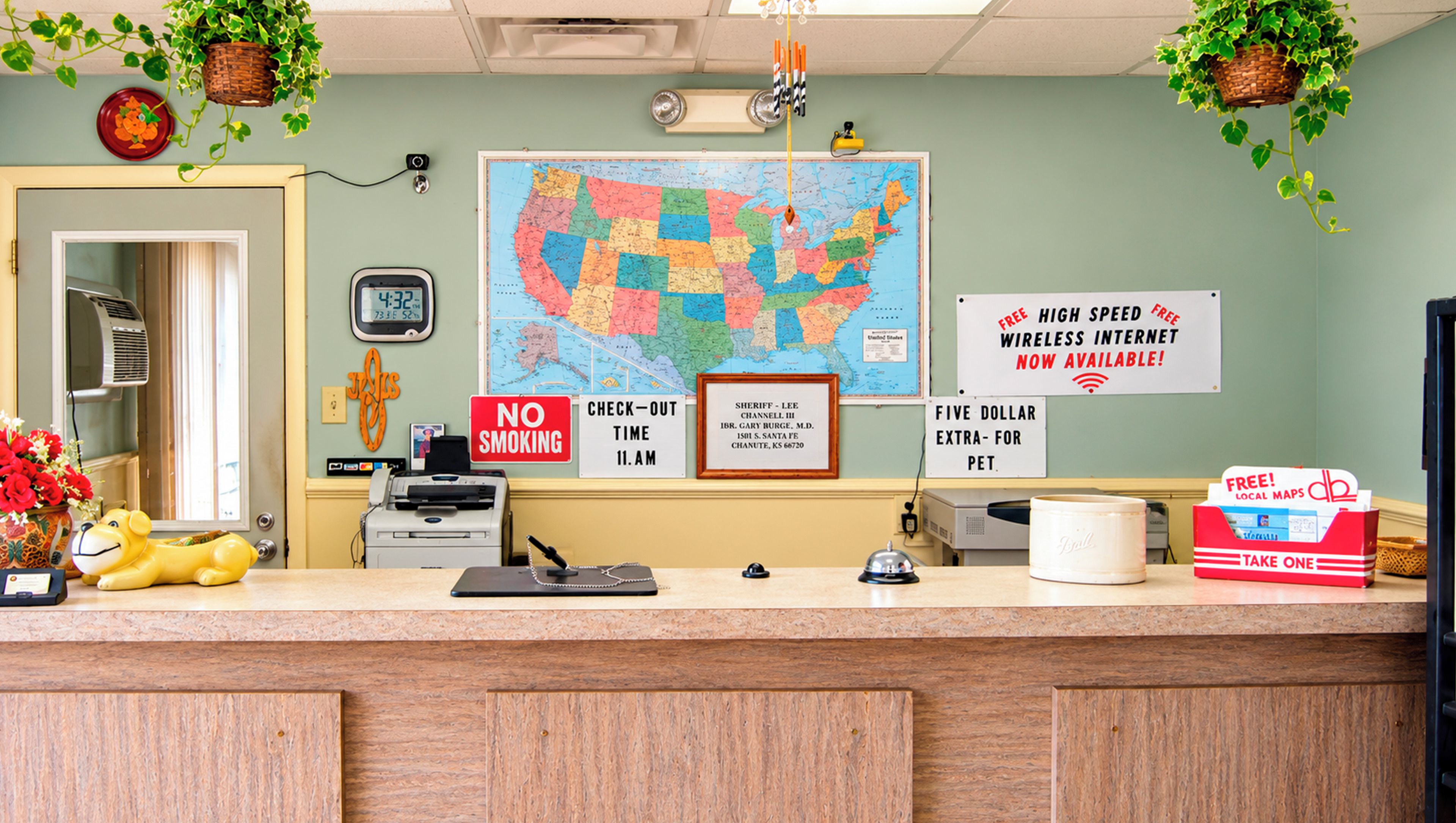 A reception desk with a map, a no smoking sign, a sheriff's nameplate, and a sign offering free high-speed wireless internet.