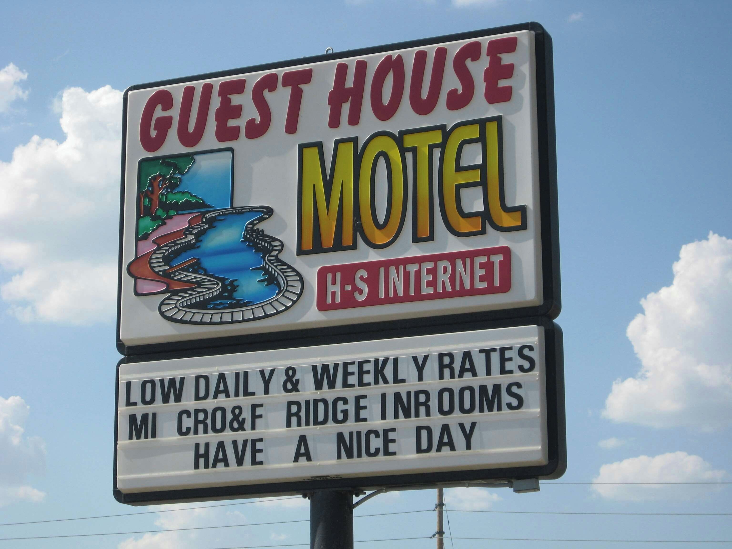 A sign for a Guest House Motel with a scenic image of a roller coaster, indicating a fun theme.