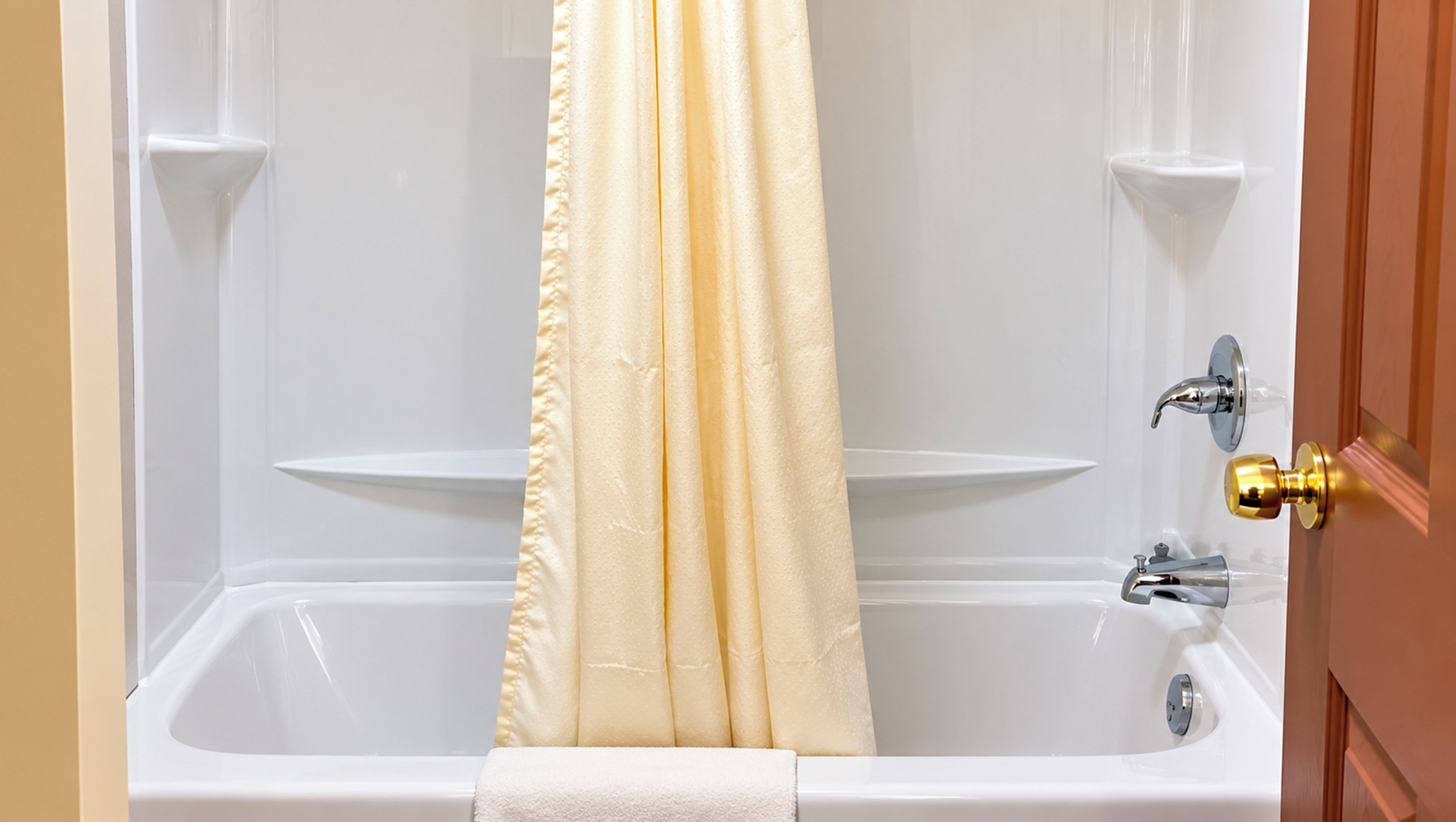 A bathroom with a bathtub, a shower curtain, and a towel rack.
