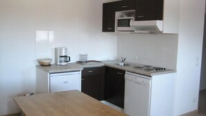 A compact kitchen with a dishwasher, a coffee maker, a microwave, and a stove.