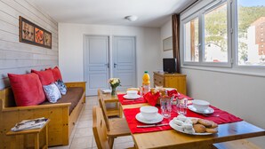 A cozy room with a wooden bench, a dining table set with plates, glasses, and a red table runner.