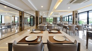 A spacious dining area with tables set for two, large windows, and a modern interior design. - BS RESIDENCE Suvarnabhumi (Bangkok)