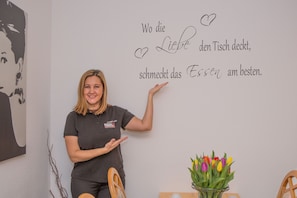 A person in a hotel uniform standing next to a wall with a German phrase and a heart symbol.