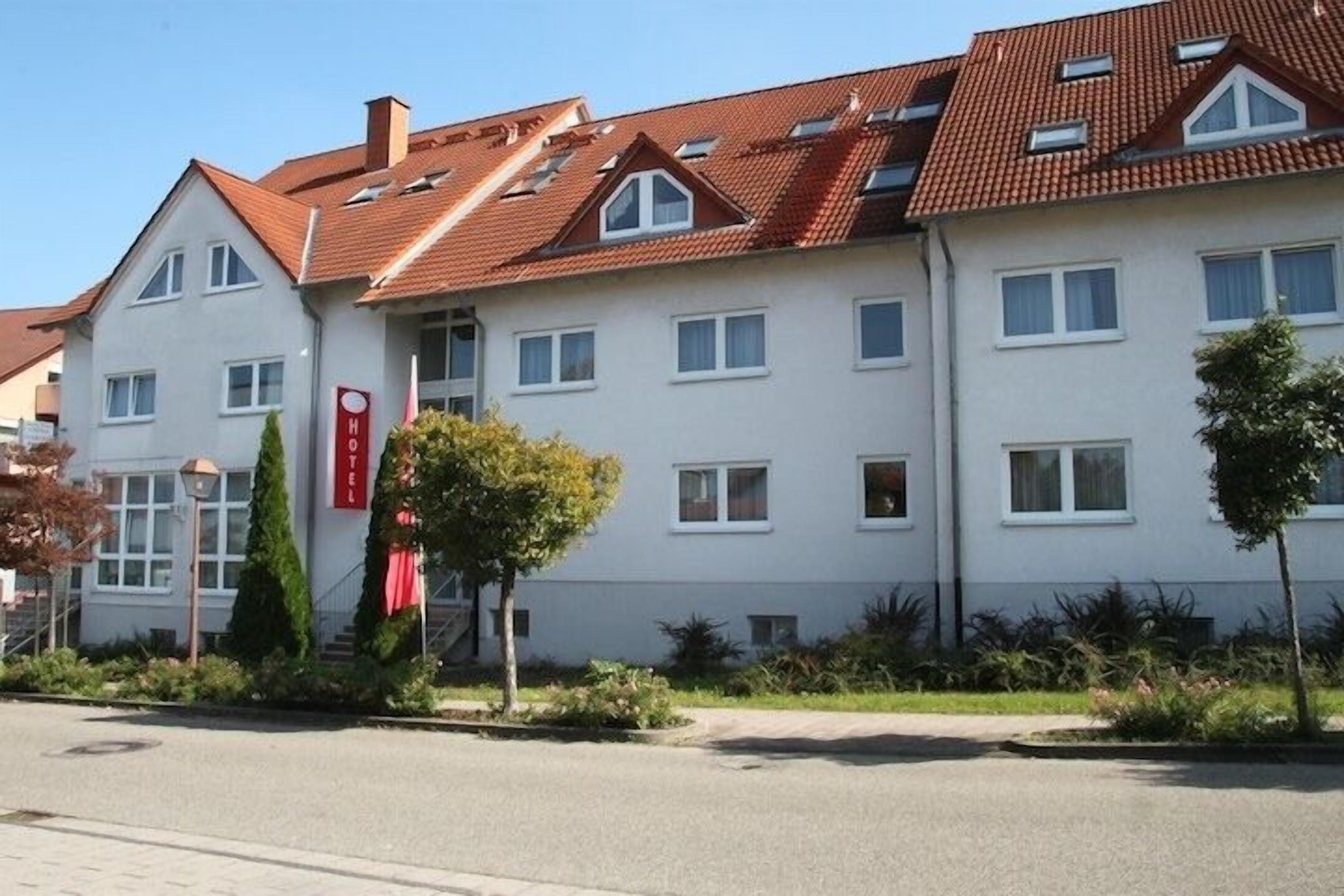 A two-story hotel with a red-tiled roof, multiple windows, and a red sign indicating it is a hotel.