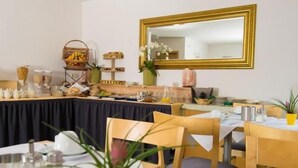 Un comedor con mesas y sillas de madera, un bufé con diversas opciones de comida y un espejo grande en la pared.