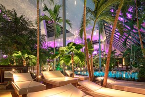 A poolside area with lounge chairs and palm trees, surrounded by lush greenery. - Hotel Leo Mühlhausen (Muehlhausen)
