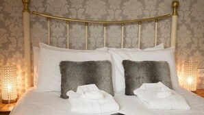 A neatly made bed with white linens, two fluffy gray pillows, and a black tablet on the bed. - Ellerbrook House (Windermere)