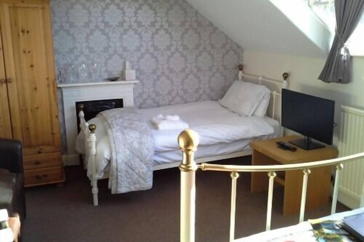 A bedroom with a bed, a television, a desk, and a wardrobe.