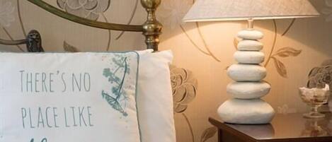 A bedroom with a bed, a bedside lamp, and a wall with floral wallpaper.