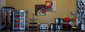 A kitchen with a toaster, coffee maker, and a display case with pastries. - Saxony Motel (Chatham-Kent)