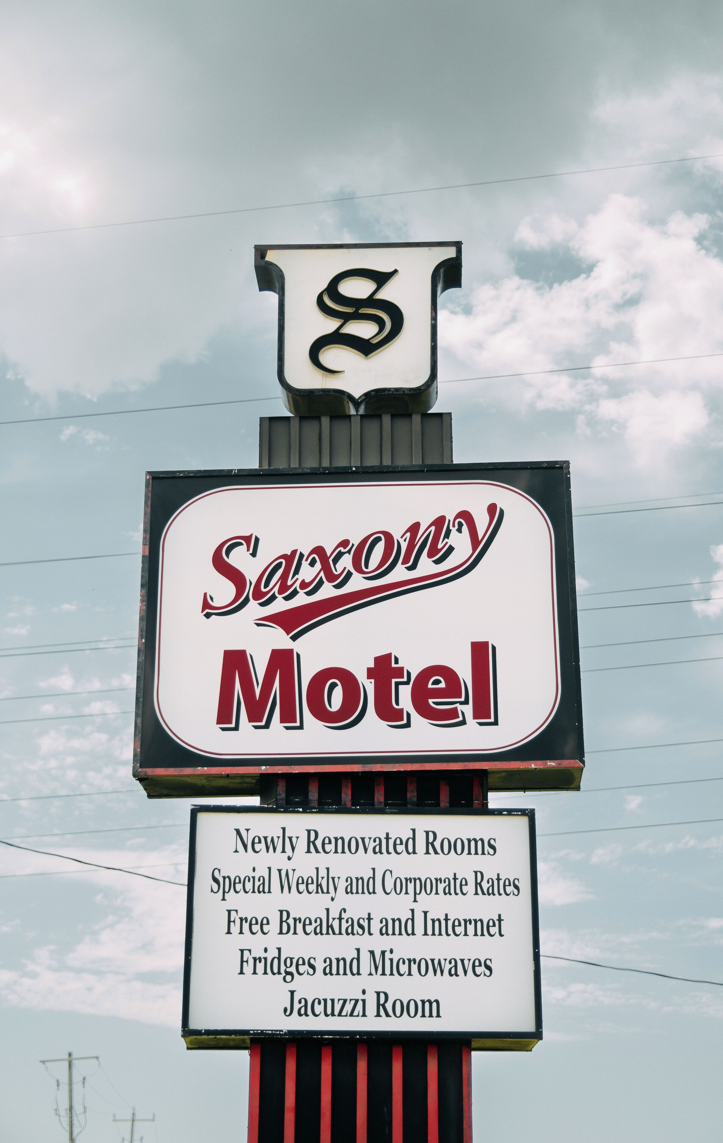 A motel sign with the name 'Saxony Motel' and mentions newly renovated rooms, special rates, free breakfast, internet, fridges, microwaves, and a Jacuzzi room.