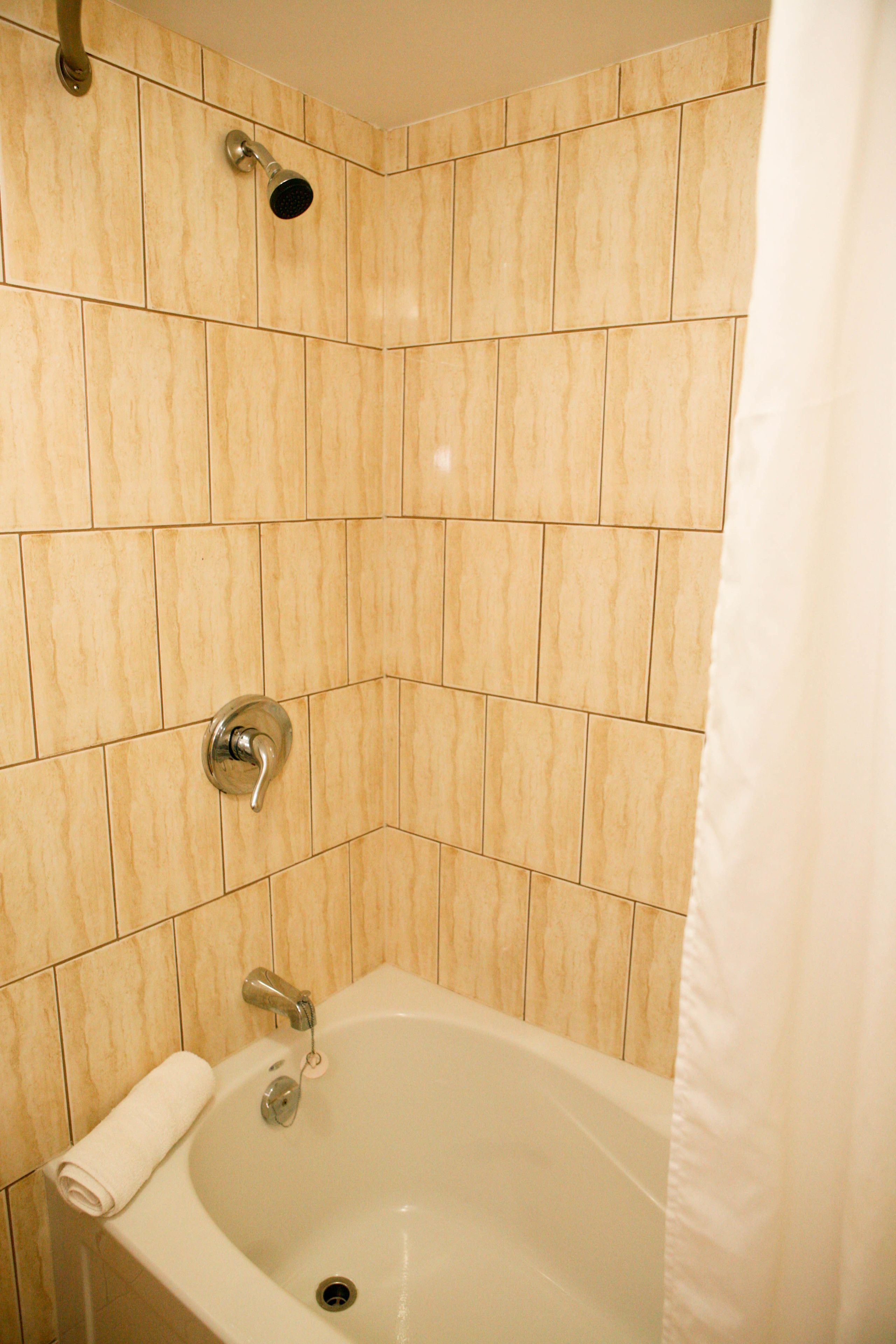 A bathroom with a bathtub, a showerhead, and a towel on the side.