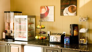 Una encimera de cocina con cafetera, tostador y una exposición de fruta.