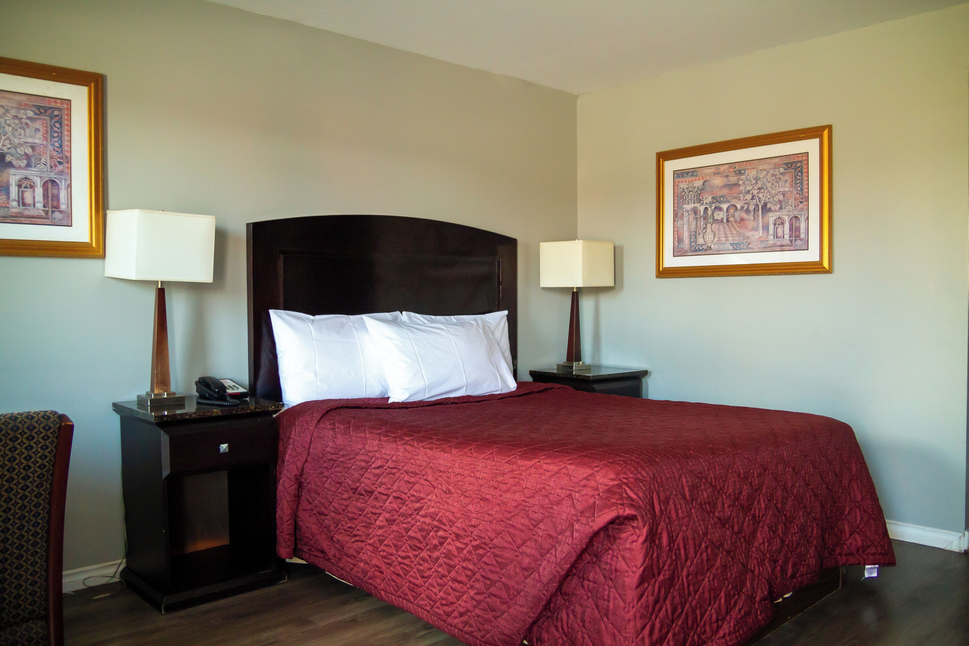 A hotel room with a large bed, two bedside tables with lamps, and two framed pictures on the walls.