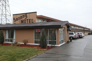 Un motel avec une enseigne indiquant « Saxony Motel » et une autre enseigne indiquant « OUVERT ». Plusieurs voitures sont garées devant.
