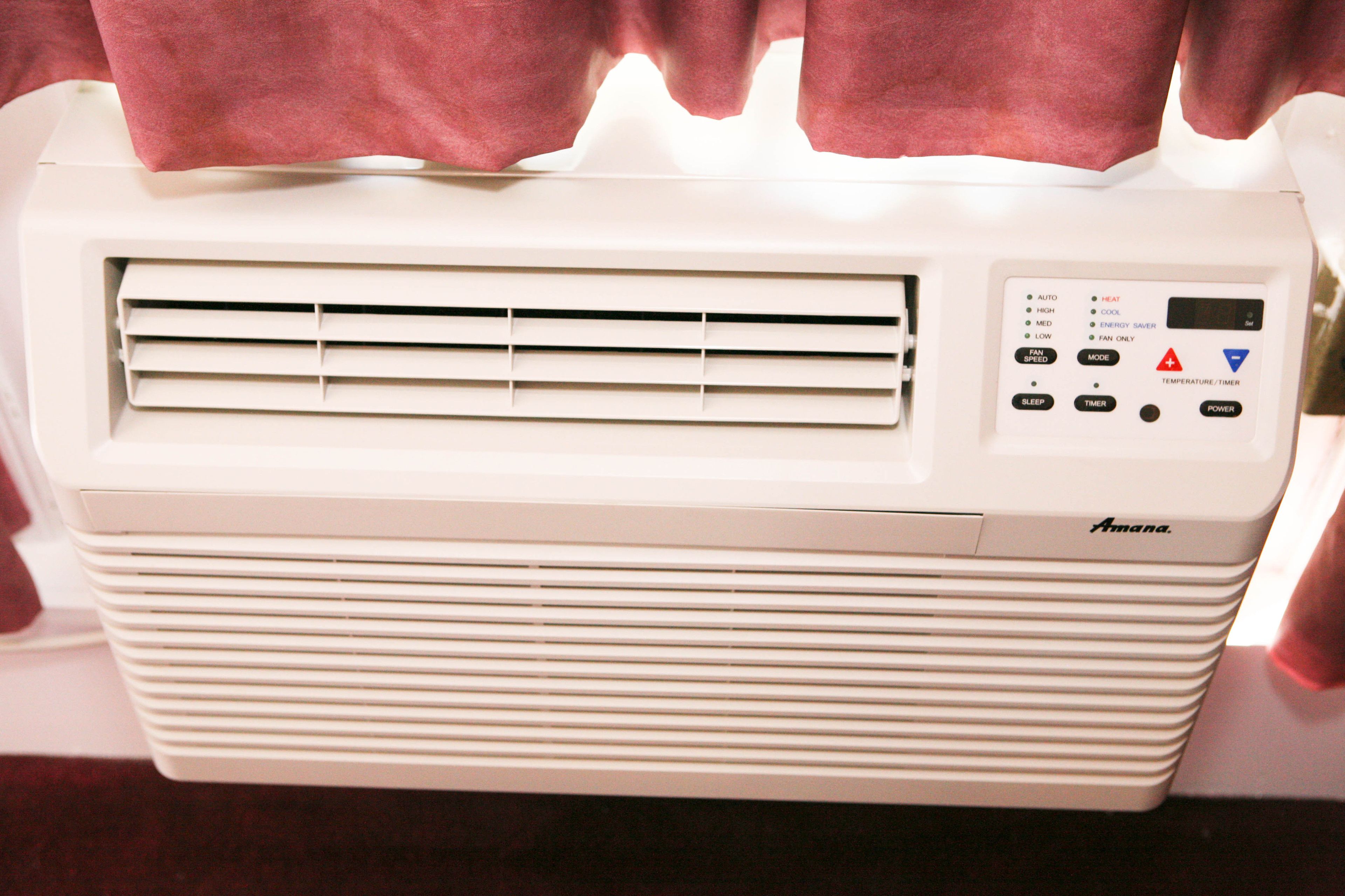 A white portable air conditioner with a control panel featuring temperature settings, a power button, and a timer.