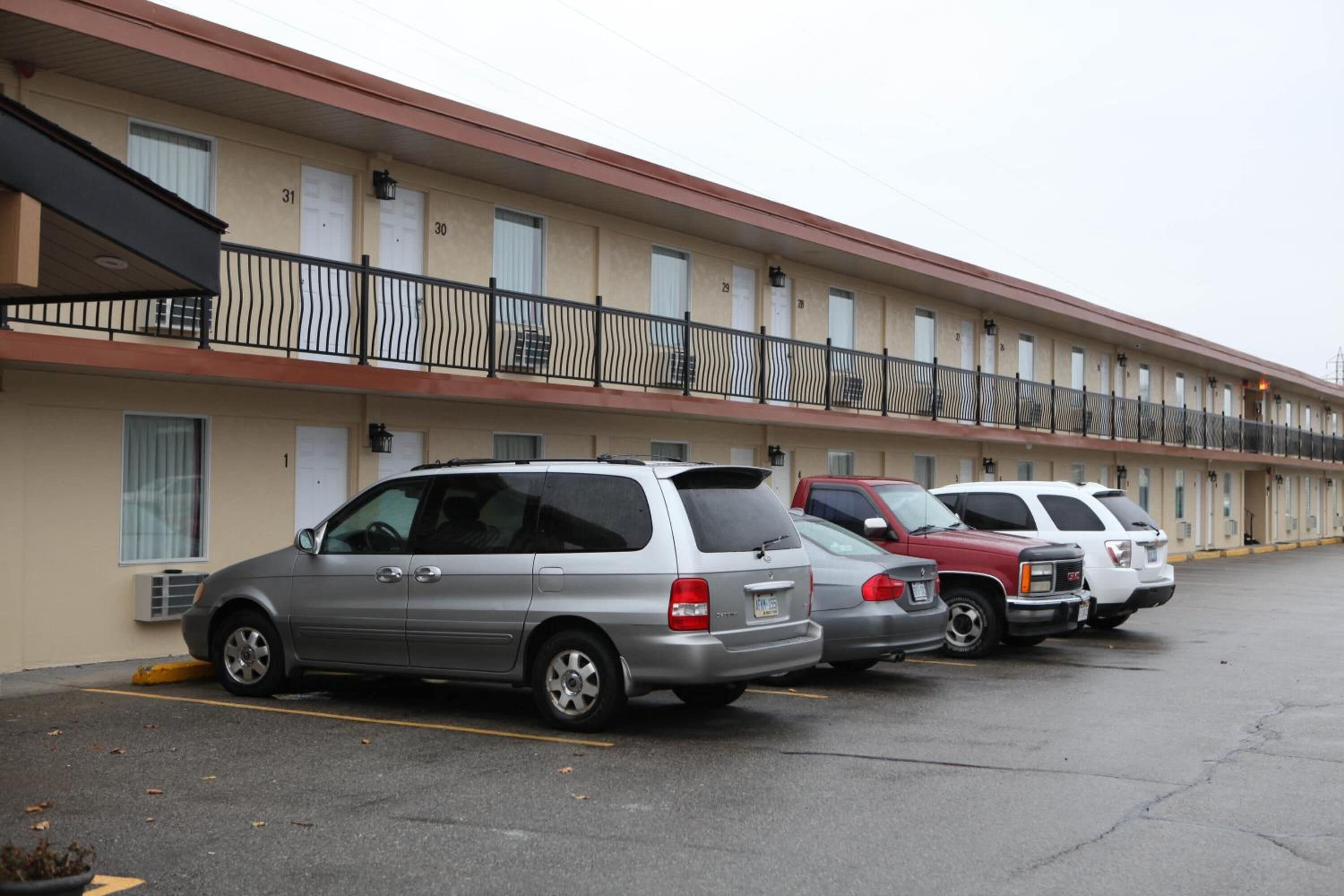 A motel with multiple parking spaces and a row of rooms on the ground floor.