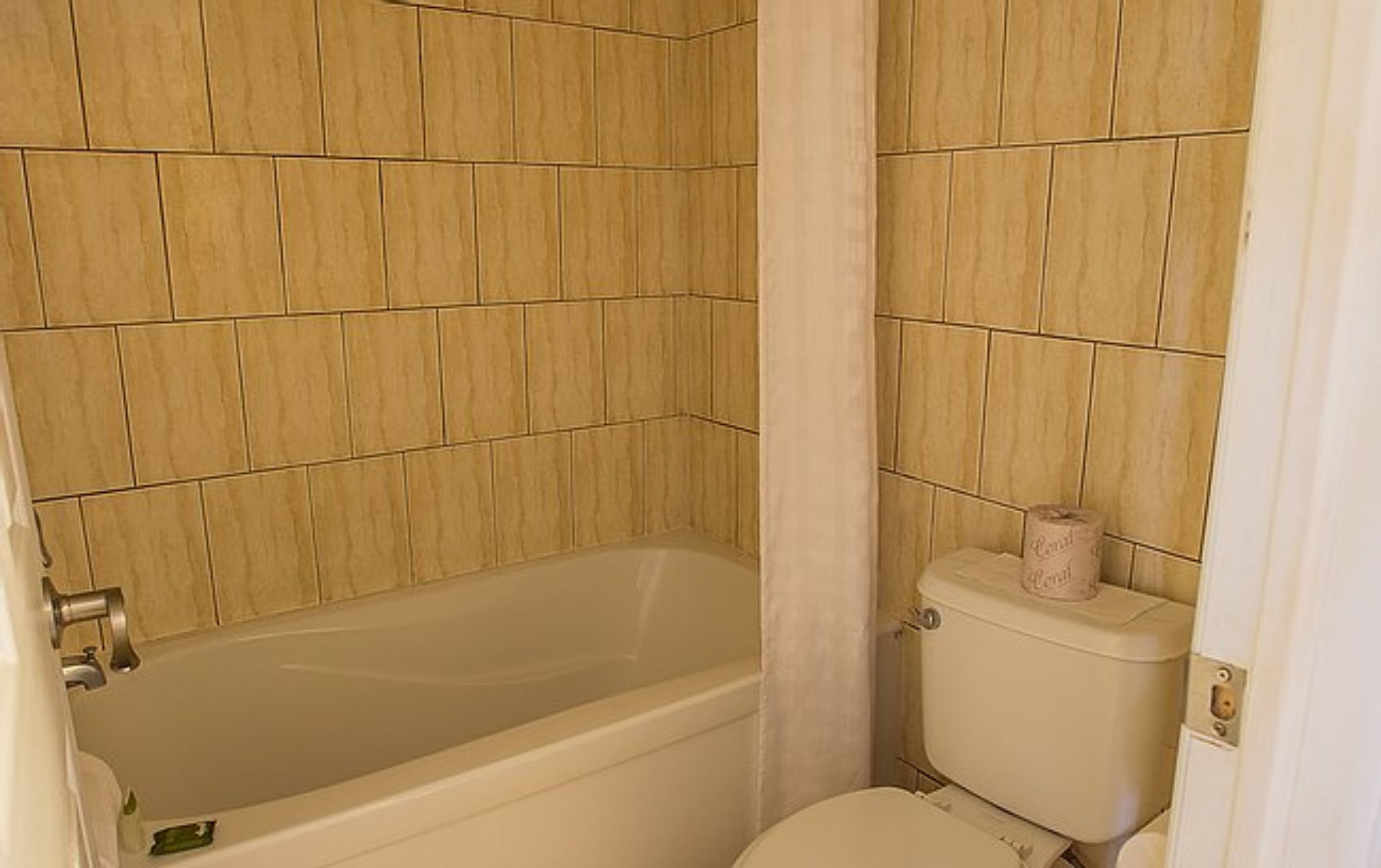 Un baño con bañera, inodoro y paredes de azulejos.