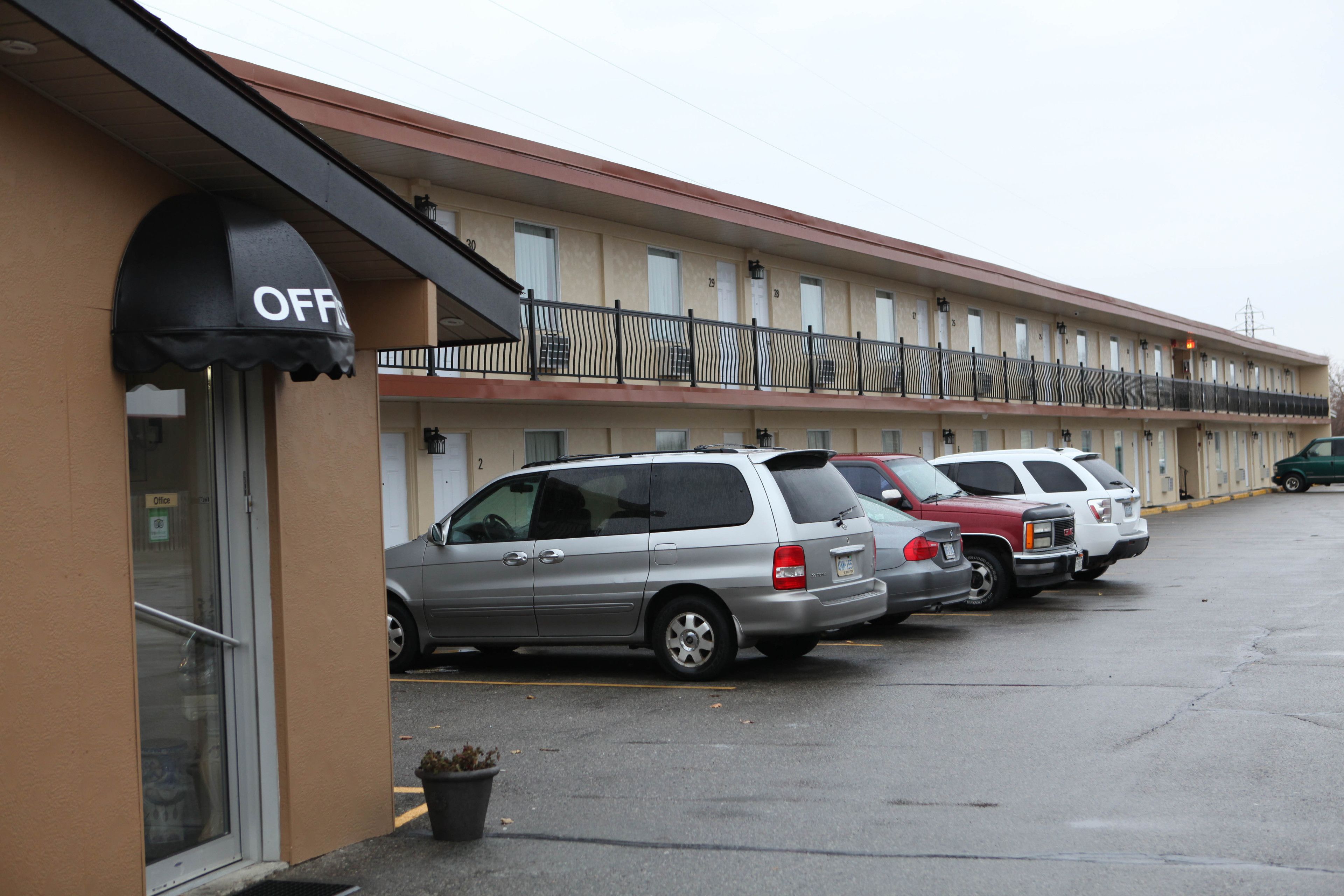 Un motel avec une rangée de voitures garées et une entrée clairement visible.