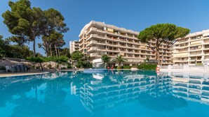 Un hôtel doté d’une piscine, entouré d’arbres et offrant une vue sur un ciel dégagé.