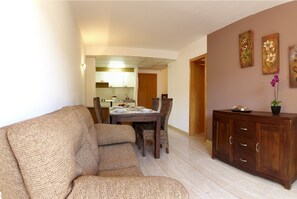 A living room with a sofa, dining table, chairs, and a wooden cabinet.